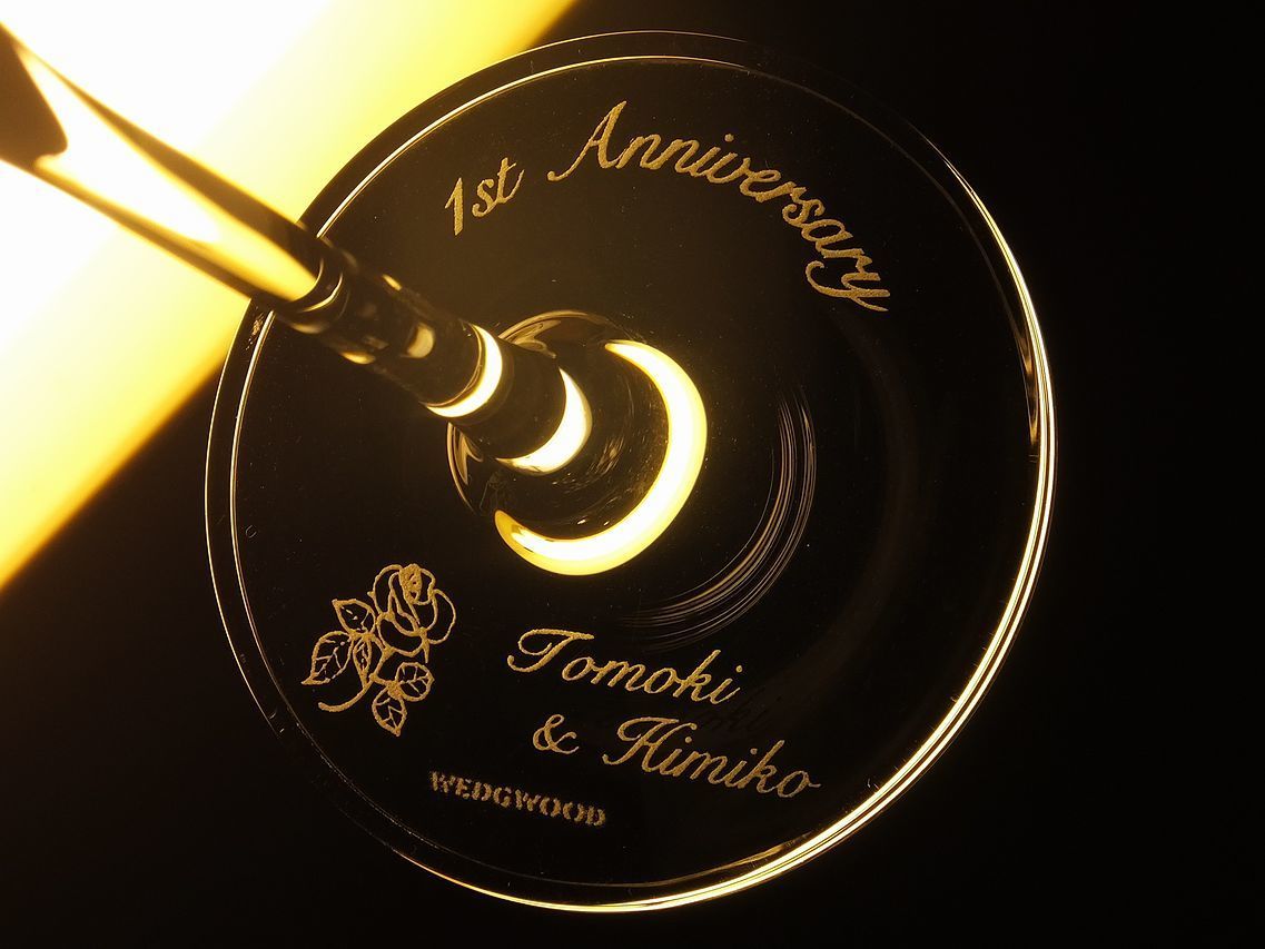 ウエッジウッドのプロミシストゥーハーツシャンパングラスの底面に、結婚1周年を祝うメッセージとお二人の名前を名入れ彫刻。ワンポイントのお花のデザインがアクセントとなり、記念日にふさわしい上品で特別なグラスギフト