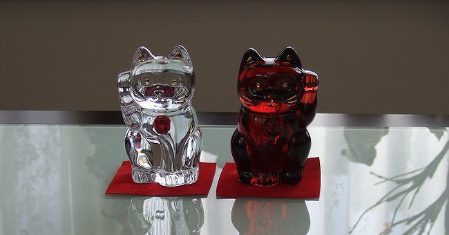 テーブルの上に置かれたバカラの2体の招き猫。右手を上げた胸の鈴がレッドオクトゴンの招き猫と、左手を上げたレッドカラーの招き猫が、精緻なクリスタルで作られ、幸運と繁栄を招く縁起物としてインテリアを彩る