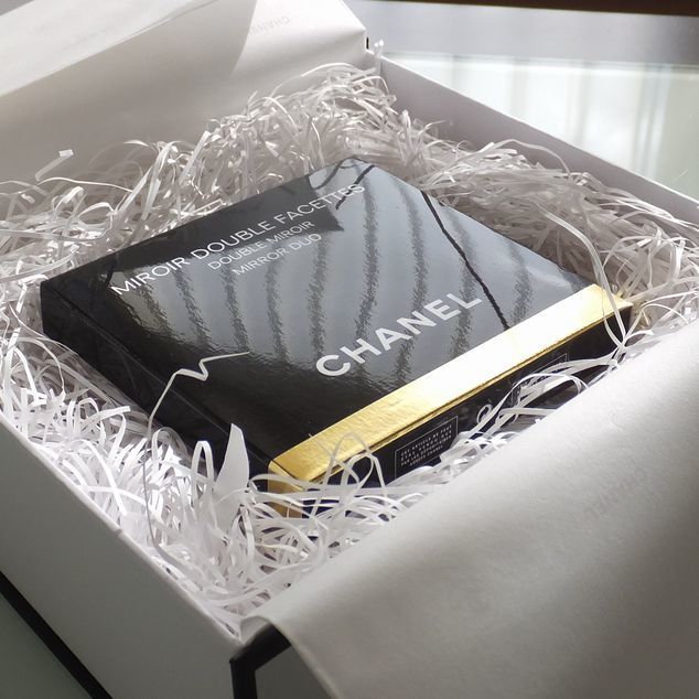 シャネルのコンパクトミラーを専用のギフトボックスに入れた写真。ブランドの象徴的なパッケージが、贈り物としての高級感と特別感を際立たせています。