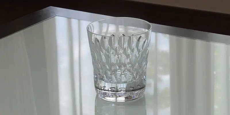 バカラのタンブラー（ロックグラス）の名入れページの商品一覧で使用する写真。バカラ アルマニャックタンブラーがテーブルの上に置かれています。宝石のように美しく輝きが特徴的なグラスが光を反射し、名入れギフトとしての存在感と洗練された美しさを演出しています。