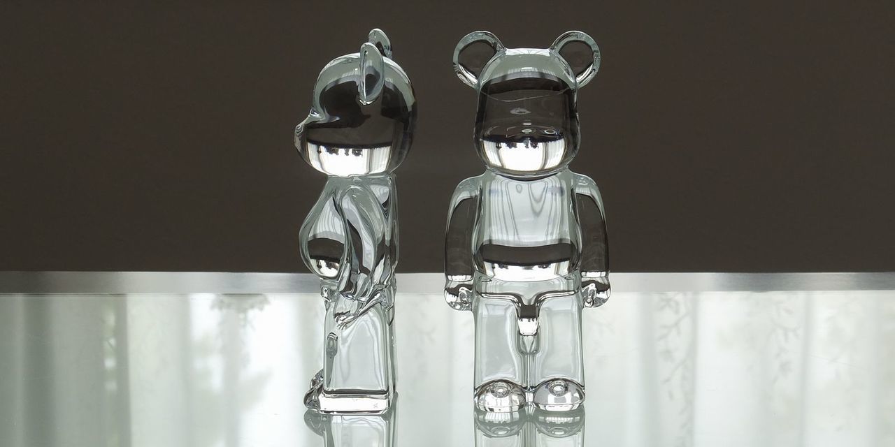 バカラのベアブリック2体が、テーブルの上に置いてある写真。透明なクリスタル製のベアブリックが2体並び、それぞれの個性と、クリスタルの透明感が光を反射して輝いています。名入れギフトとしても、コレクターズアイテムとしても魅力的な逸品です。