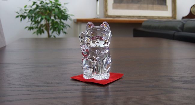 デスクの上に置かれたバカラのクリスタル製右手を上げた招き猫。精緻なデザインと輝きが、幸運と繁栄を招く縁起物としてオフィスやインテリアを彩る高級感あふれるアイテム