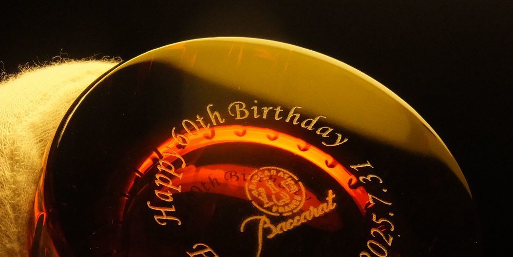 バカラグラスのハーモニータンブラー レッドの底面に、『Happy 60th Birthday 名前 日付』を名入れ彫刻した写真。深みのある赤色のクリスタルの底面に、還暦を祝う温かいメッセージが繊細に刻まれ贈る人生の節目を彩る、特別な記念品としての価値と、洗練された美しさを際立たせています。