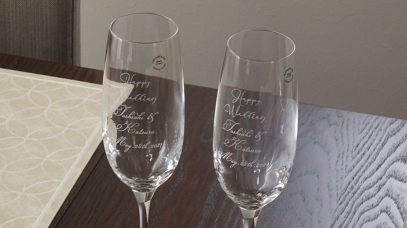 ティファニーシャンパンの側面にスクリプト体で刻まれたご結婚祝いのメッセージ、お二人の名前と記念日。優雅な彫刻が贈り物としての特別感を引き立て、記念すべき瞬間を華やかに彩る