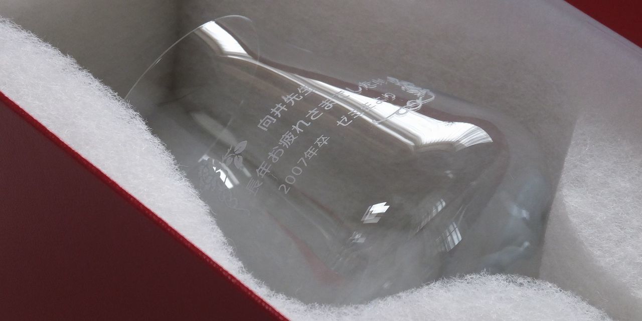 シャトーバカラワイングラスの側面に、『向井先生 長年お疲れ様でした ２００７年卒 ゼミ生より』と名入れ彫刻した写真。高品質なクリスタルに刻まれた感謝のメッセージが、先生への特別な贈り物としての温かい気持ちを伝えています。
