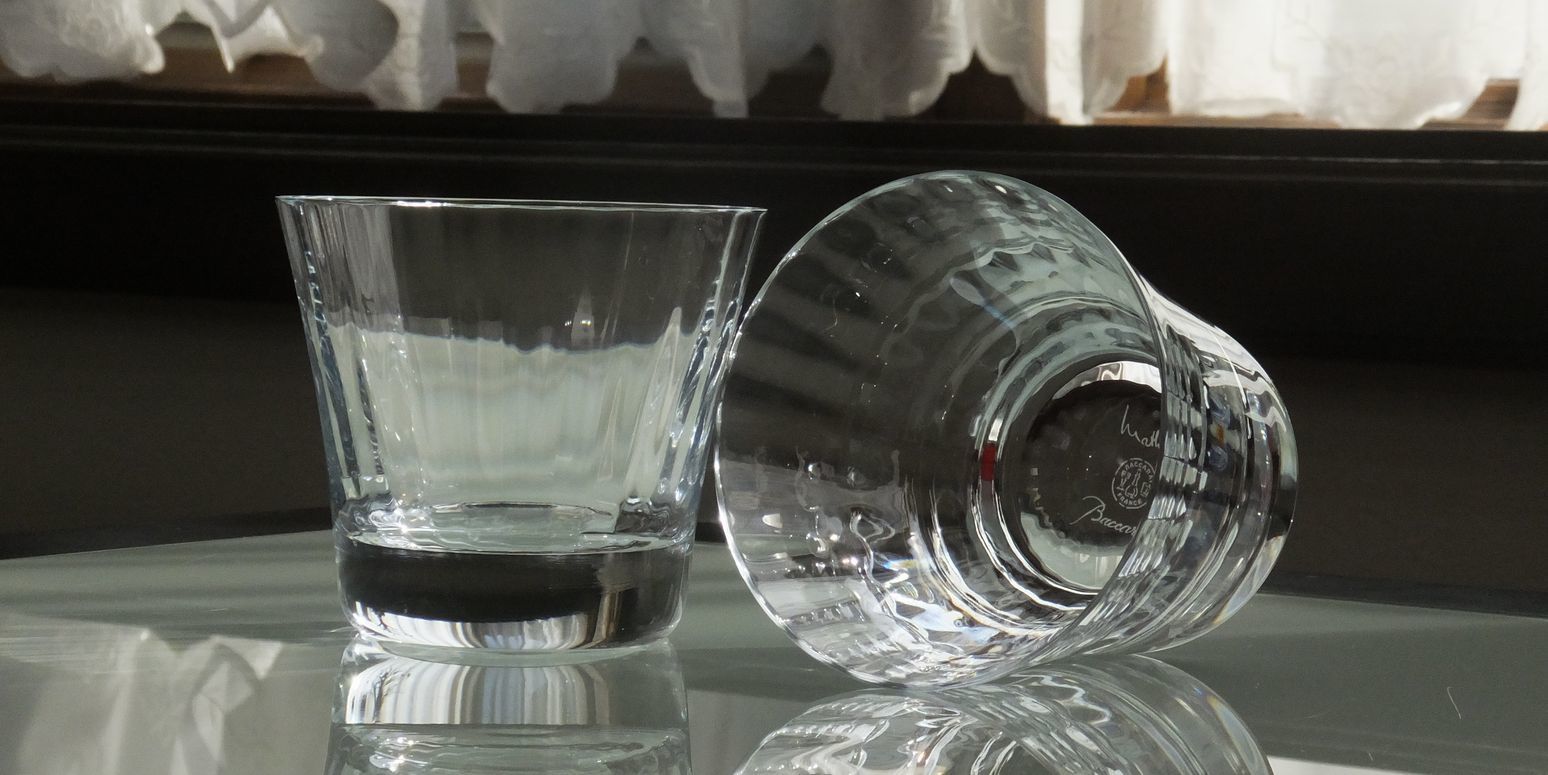 バカラの『ミルニュイ タンブラー ペア』が、木製のテーブルやモダンな食卓の上に並べられている様子の写真。アラビアンナイトをイメージしたミルニュイ特有の、プリーツ状の美しいカットが施された2つのタンブラーが、仲良く寄り添うように配置されている。カットが光を反射し、豪華さとロマンチックな雰囲気を演出し、結婚祝いや記念日のペアギフトとしての特別な価値を視覚的に伝えている。