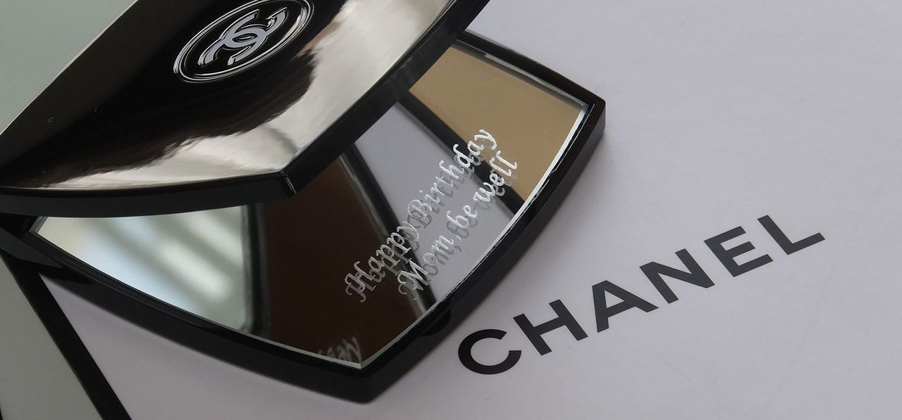 シャネルのコンパクトミラーの下のミラー中央に、『Happy Birthday Mom,be well』と名入れ彫刻を施した写真。洗練されたデザインにパーソナルなアクセントが加わり、特別な母への贈り物です。