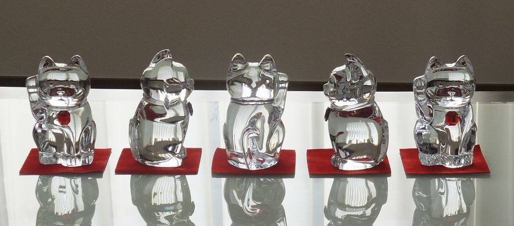 「テーブルの上に並んだバカラの招き猫5体が4方向を向いているシーン。精緻なクリスタル製の招き猫が、幸運を呼び込む縁起物として、高級感と美しさを兼ね備えたインテリアアイテム