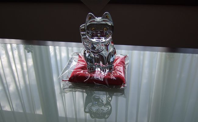 バカラの招き猫Mサイズが赤い座布団の上に丁寧に置かれた写真。クリスタルの輝きと縁起の良い赤い座布団が調和し、高級感と福を呼ぶ華やかなインテリアギフトとして魅力を放つ
