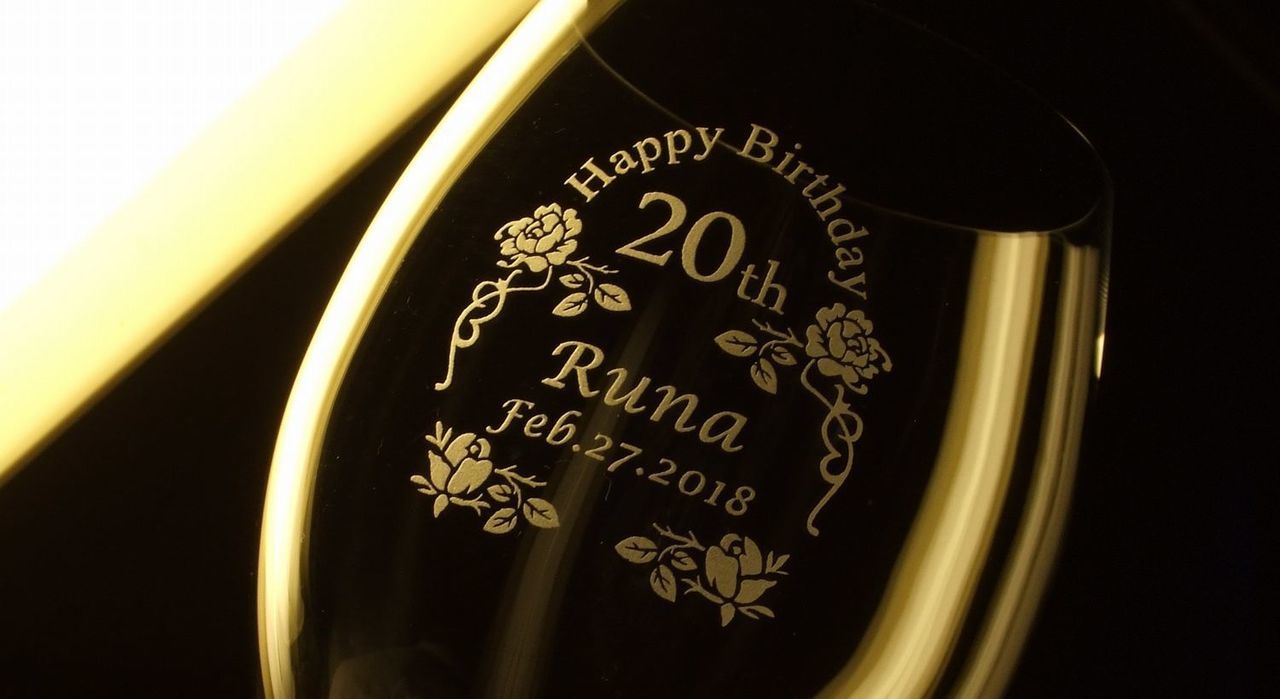 バカラのオノロジー ボルドーの側面に、『Happy Birthday 20th Runa Feb.27.2018』というメッセージをバラの花のデザインで囲んで名入れ彫刻した写真。エレガントなフォルムのワイングラスに、20歳の誕生日を祝う特別なメッセージと名前、日付が丁寧に刻まれています。大切な方の人生の節目を祝う、心に残る特別な贈り物です。