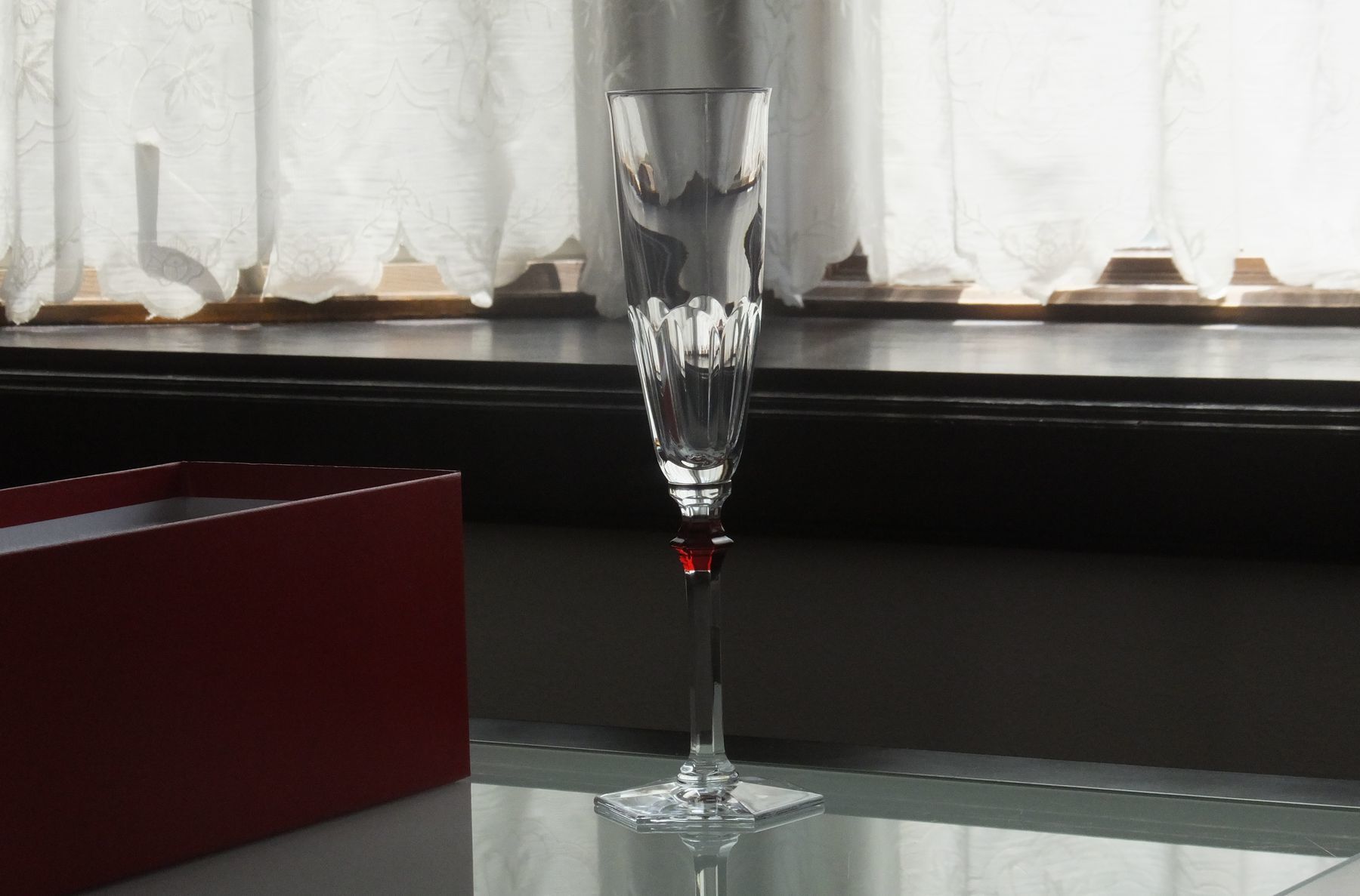 テーブルの上に置かれたバカラ（Baccarat）の『アルクール イヴ シャンパンフルート』の写真。伝統のアルクールを現代的でエレガントなフォルムに仕上げた繊細なステムとカットが光を優美に反射し、結婚祝いや記念日、特別な日の乾杯を華やかに彩る最高峰のクリスタルグラスならではの格調高いイメージ。