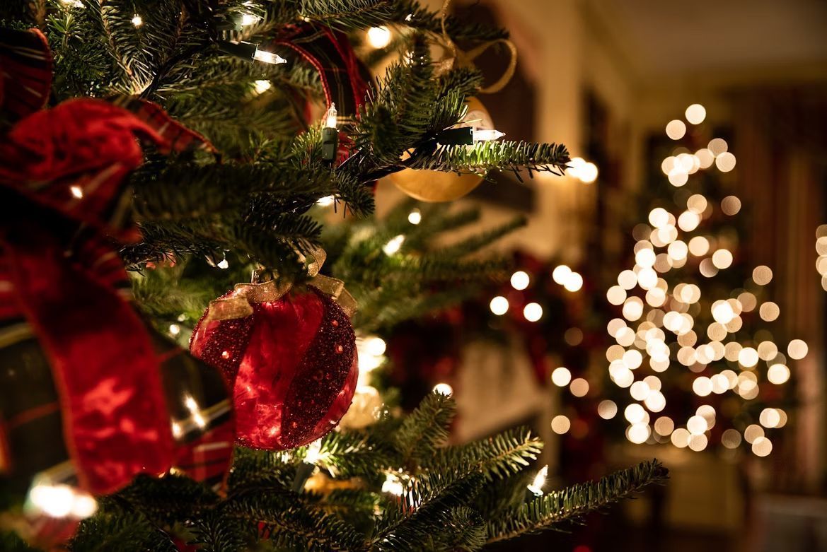 煌めくクリスマスツリーのクローズアップ。お客様からの名入れ彫刻ギフトが、まるでサンタからのプレゼントのように、大切な方へ笑顔と喜びを届けますようにとの願いを込めて