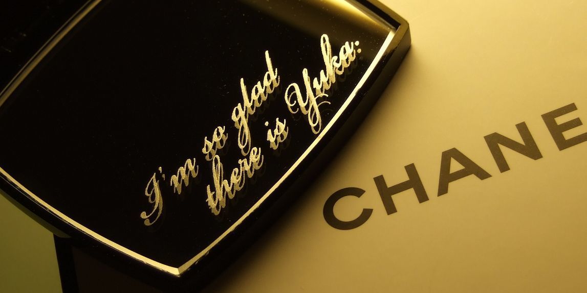 シャネルのコンパクトミラーに『I'm so glad there is Yuka』と名入れ彫刻を施した写真。大切な人への感謝や愛情を伝える、パーソナルで心温まるギフトの細部が際立っています。