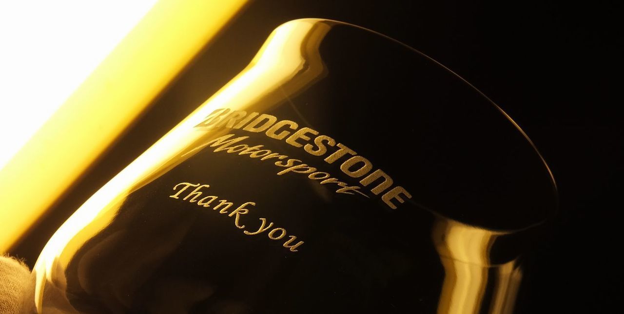 バカラのシャトータンブラーLの側面に、『BRIDGSTONE Motorsport』のロゴと『Thank you』という文字を名入れ彫刻した写真。ワインの香りを最大限に引き出すエレガントなグラスに、これまでの功績を称え、感謝を伝えるメッセージが丁寧に刻まれています。大切な方の新たな門出を祝う、特別な退職祝いにふさわしい記念品です。