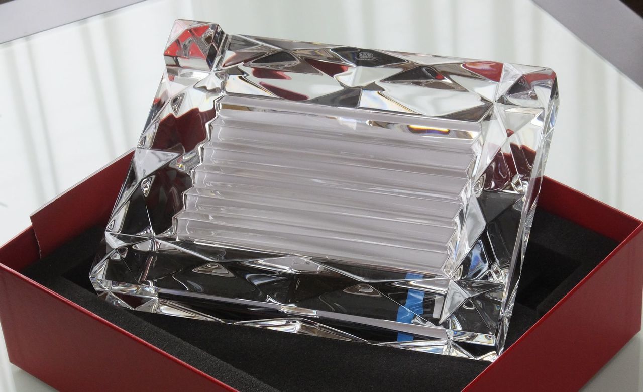バカラ（Baccarat）の『ルクソール フォトフレーム』の背面に見られる、幾何学的な凹凸とノコギリの刃（鋸歯状）のように精緻に刻まれた立体カットのディテール写真。光を複雑に屈折させて正面から見た際に眩い輝きを生み出す背面カットの構造美と、職人技による重厚なクリスタルガラスの滑らかな質感・造形美を捉えた、最高級写真立てならではの屈折効果とグラフィックな美しさを際立たせるクローズアップイメージ。