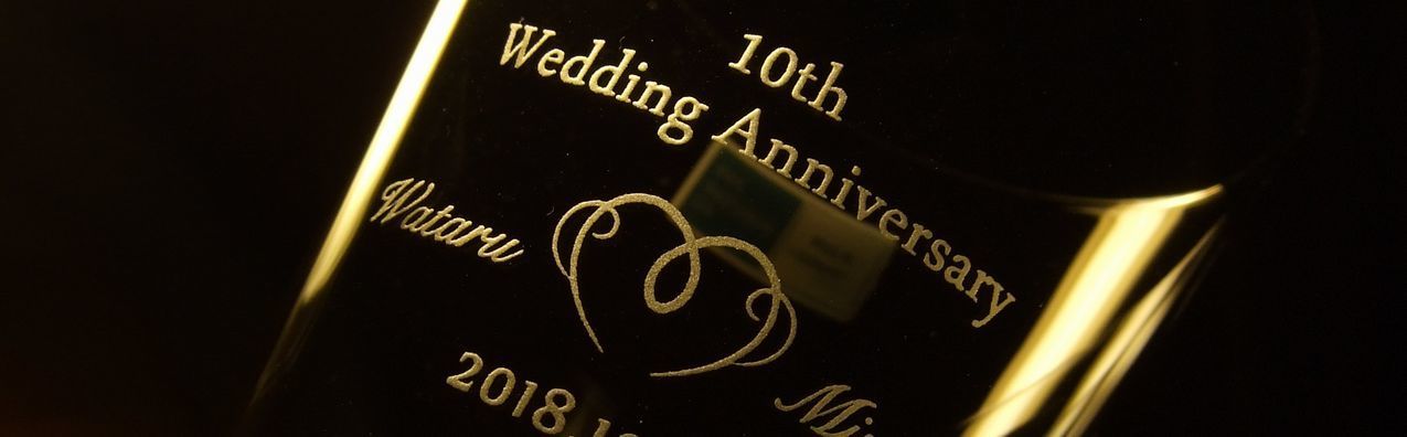 バカラハイボールグラスの側面に「10th Wedding Anniversary」の文字とお二人の名前でオリジナルのハートデザインを挟んだ名入れ彫刻。愛と絆を祝う特別な10周年記念の贈り物