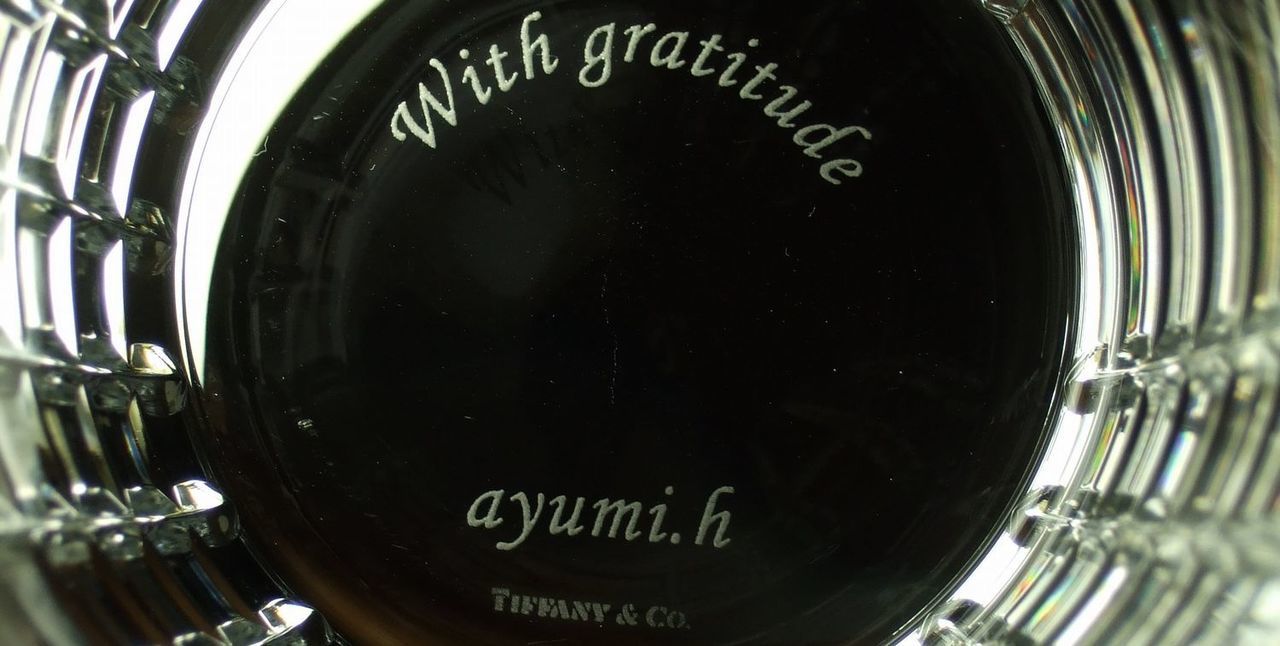 ティファニーグラスの底面に、『With gratitude ayumi.h』と名入れ彫刻した写真。ティファニーブルーのボックスに収められた美しいグラスの底に、感謝のメッセージが繊細に刻まれています。大切な人への感謝を伝える、心に残る特別な贈り物にふさわしい逸品です。
