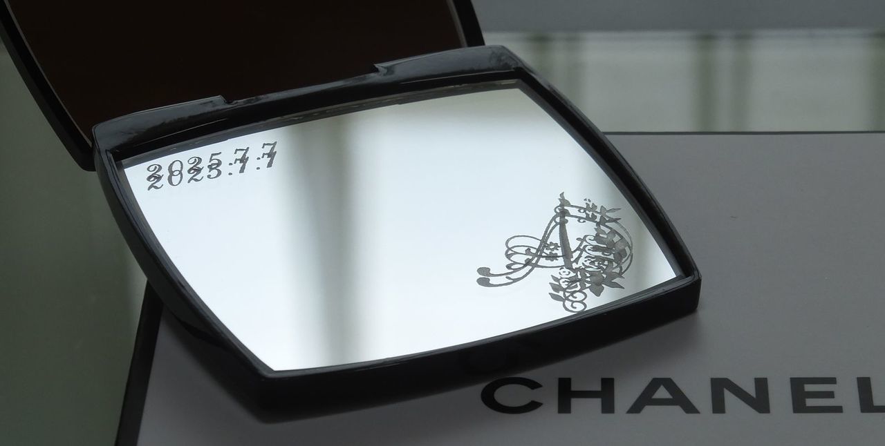 シャネルのコンパクトミラーに、イニシャルデザイン『A』と『2025.7.7』という日付を名入れ彫刻した写真。シャネルの象徴的なデザインに、パーソナルなイニシャルと記念日が刻まれた特別な贈り物です。誕生日や記念日、または特別な日の感謝を伝えるギフトに最適です。