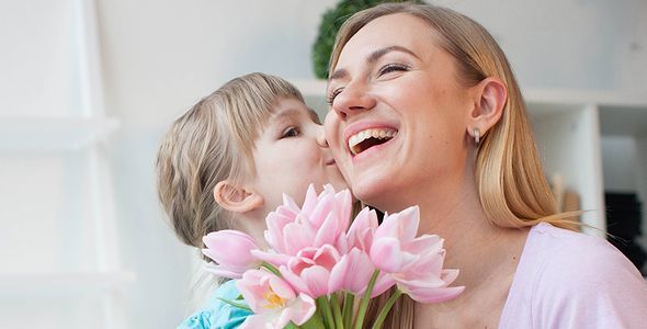 母の日にぴったりの名入れギフト｜子どもが母の頬にキスしながら花を贈る笑顔の瞬間