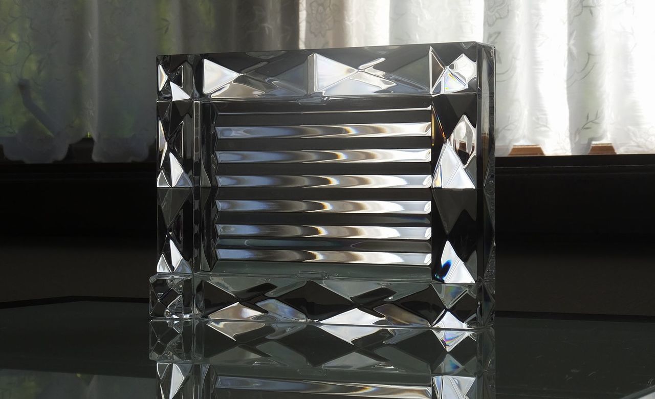 バカラ（Baccarat）の『ルクソール フォトフレーム』を、背面の幾何学的な凹凸やノコギリの刃（鋸歯状）のような立体カットの面を前面に向けてテーブルの上に配置した写真。