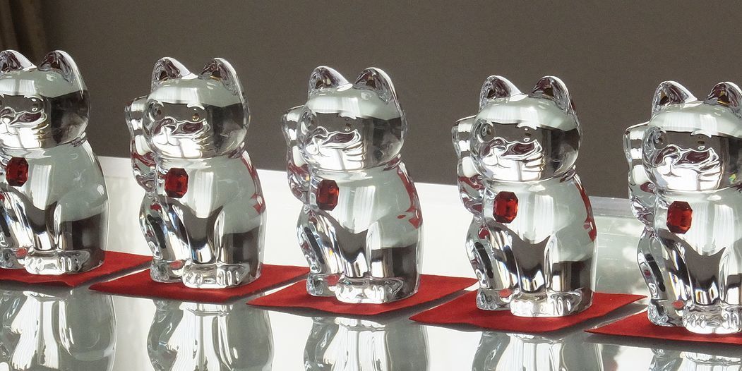 バカラの招き猫 レッドオクトゴンが5体、テーブルの上に置いてある写真。胸に八角形の台座を持つ赤いクリスタル製の招き猫たちが、空間に活気と幸運をもたらす存在感を放っています。