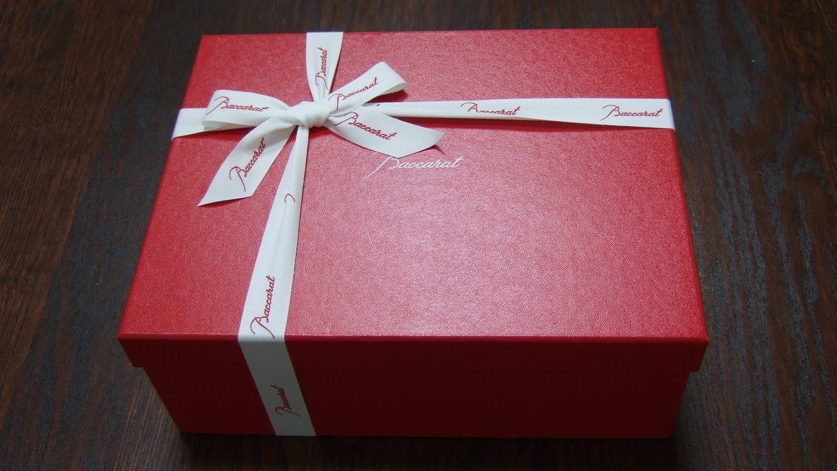 白いリボンが美しく結ばれたバカラのレッドボックス。ご結婚祝いや結婚記念日、退職祝いなど、フォーマルで特別な贈り物としてふさわしい高級ギフトボックス