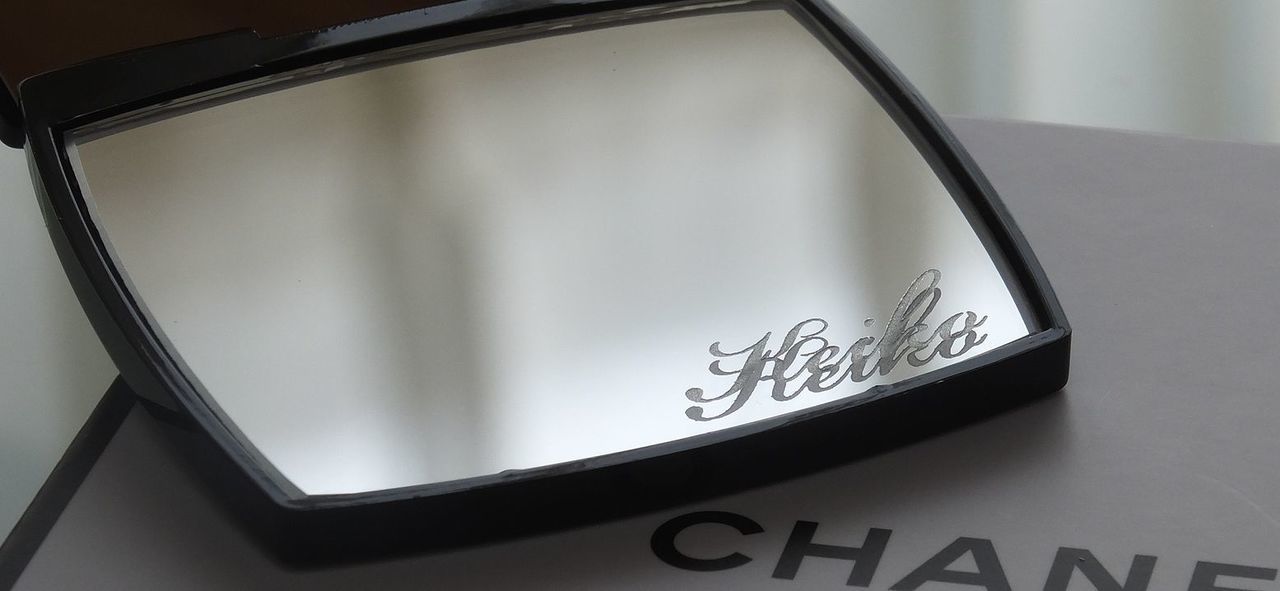 シャネルのミラー下部に、流麗なスクリプト体で『Keiko』と名入れ彫刻が施された写真。自分だけの特別感を演出する、繊細でエレガントなパーソナルギフトのイメージ。