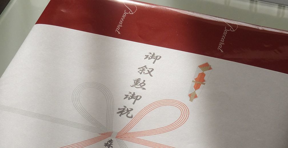 バカラの名入れ花瓶一覧で使用する写真。バカラのギンコベースの側面に、『JAPAN UNIXのロゴデザインと50th Anniversary』を名入れ彫刻した写真。イチョウの葉をモチーフにした優美なデザインのベースに、企業のロゴと50周年を祝うメッセージが格調高く刻まれ、企業の歴史と未来を象徴する特別な記念品です。