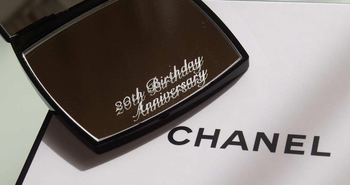 シャネルのコンパクトミラーに、20歳の誕生日を記念するメッセージを名入れ彫刻した写真。特別な誕生日を祝うエレガントなギフト、思い出に残る贈り物