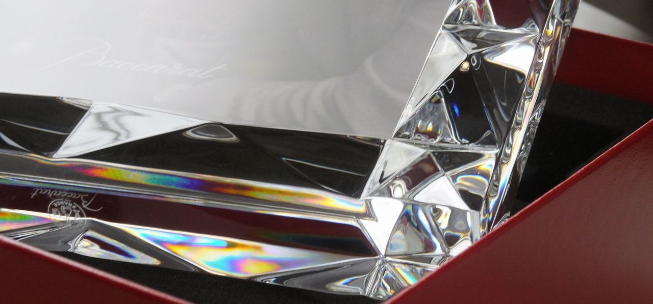 バカラ（Baccarat）の『ルクソール フォトフレーム』のフレーム部分に施された、ピラミッド状の立体的なダイヤモンドカットのクローズアップ写真。古代エジプトのルクソール神殿の建造物からインスピレーションを得た象徴的な幾何学カットが光を複雑に屈折・反射させ、最高級クリスタルガラスならではの極上の透明感と幾重にも重なる眩い輝きを放つ、洗練されたクラフトマンシップとラグジュアリーな造形美を凝縮したディテールイメージ。