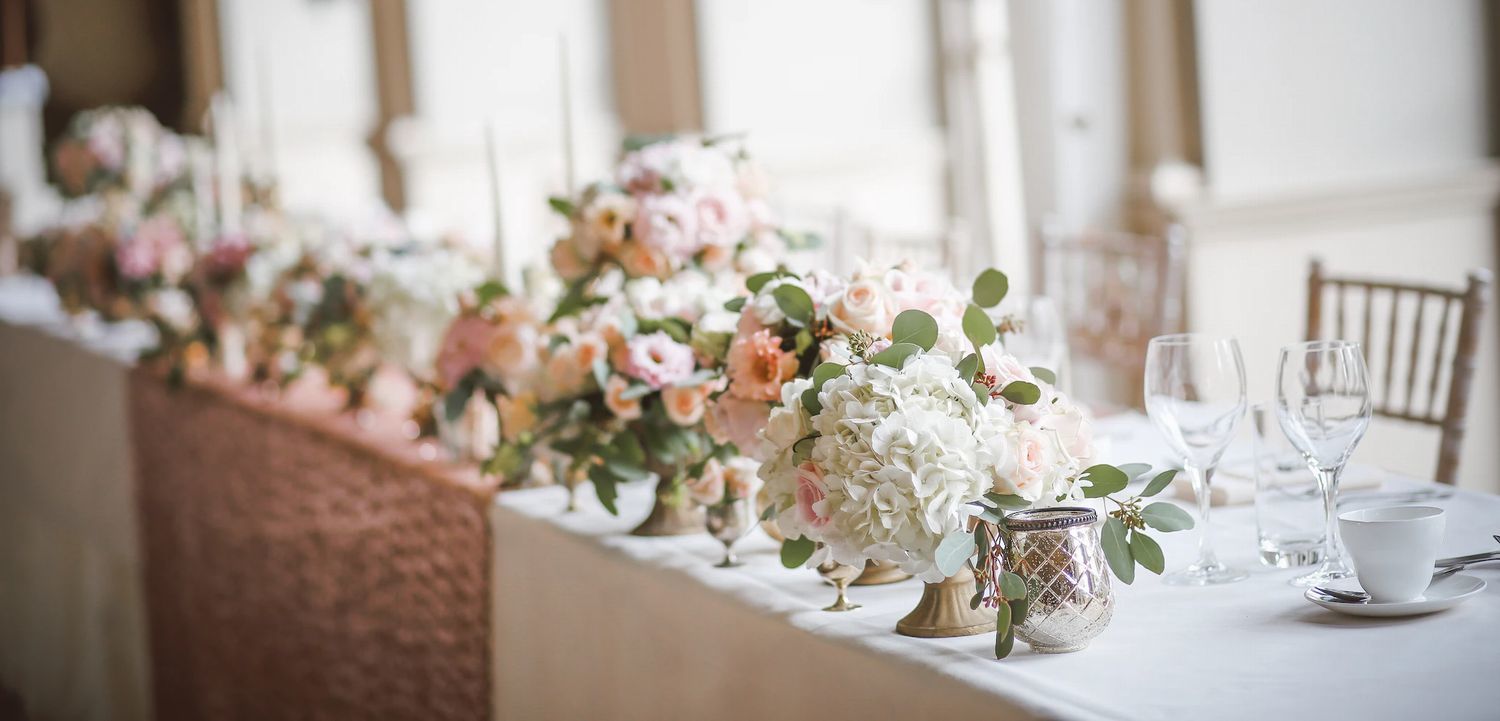 手作りの結婚式のテーブルセッティング。室内に並べられたグラスや色とりどりのお花が、温かくアットホームな雰囲気を演出し、特別な一日を華やかに彩る