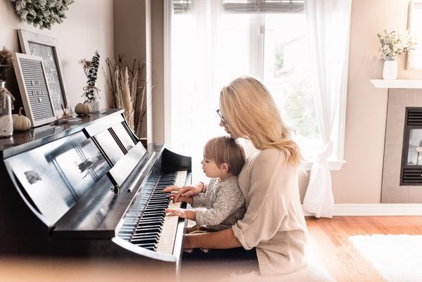 母と子がピアノを共に奏でるシーン。音楽を楽しみながら、親子の深い絆と愛情が伝わる心温まる写真