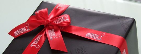 リーデルの包装紙とリボンで包まれたグラス箱の写真。リーデルの高級感あふれるラッピングが、贈り物としての特別感を一層引き立てます