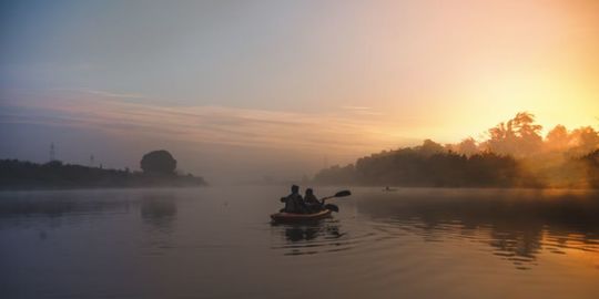 バランスを取りながら、手漕ぎボートに二人で乗って移動している写真