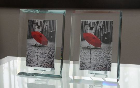 オモドモの厚みのあるエクストラガラス製フォトフレーム2種類がテーブルに並べられ、その高級感と透明感が際立つ写真。大切な思い出を飾るのにふさわしい、洗練されたデザインのフォトフレームです。