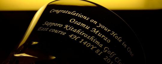 バカラ製グラスの側面にホールインワン記念の名入れ彫刻を施したオーダーメイドギフト。お名前、ゴルフ場名、コース名、使用アイアン、日付が刻まれた特別な記念品