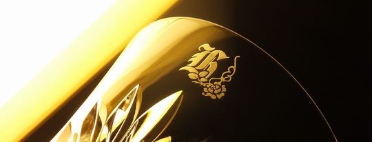 バカラのイヤーグラスアリア2025タンブラー側面に、ガラスデザインロザリオによるオリジナルのイニシャル彫刻を施した写真。スクリプト体の英字にバラの花がアイアンで吊るされた名入れが映えるオーダーメイドギフト