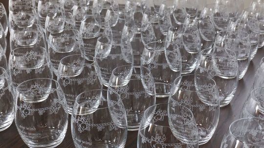 テーブルの上に多数並べられた名入れ彫刻されたウェッジウッドタンブラーの写真。法人向けや記念品に対応する高級ガラス製ギフトの大量注文イメージ