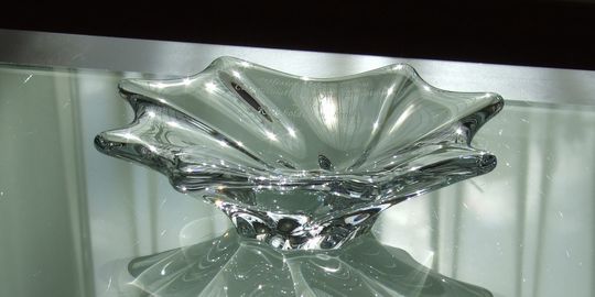 バカラの招き猫 クリアMサイズがテーブルの上に置いてある写真。透明なクリスタル製の招き猫が、その美しいフォルムと光の反射で、空間に幸運と洗練された雰囲気をもたらしています。名入れギフトとしても、インテリアとしても魅力的な逸品です。