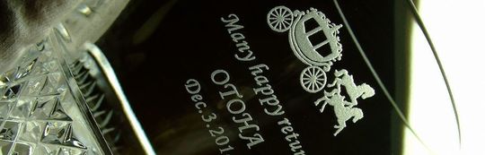 ウェッジウッドのタンブラーグラスの側面に、馬車のデザインと『Many happy returns [名前] [日付]』を名入れ彫刻した写真。誕生日や記念日のお祝いにふさわしい、エレガントでパーソナルなギフトのイメージです。