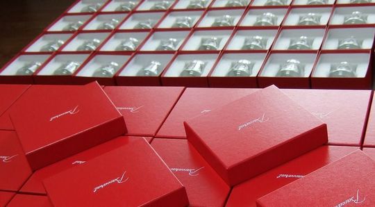 大量のレッドボックスと、レッドボックスに入ったバカラロックグラス50個以上が並ぶ写真 高級感あふれる記念品やギフトの大量注文事例