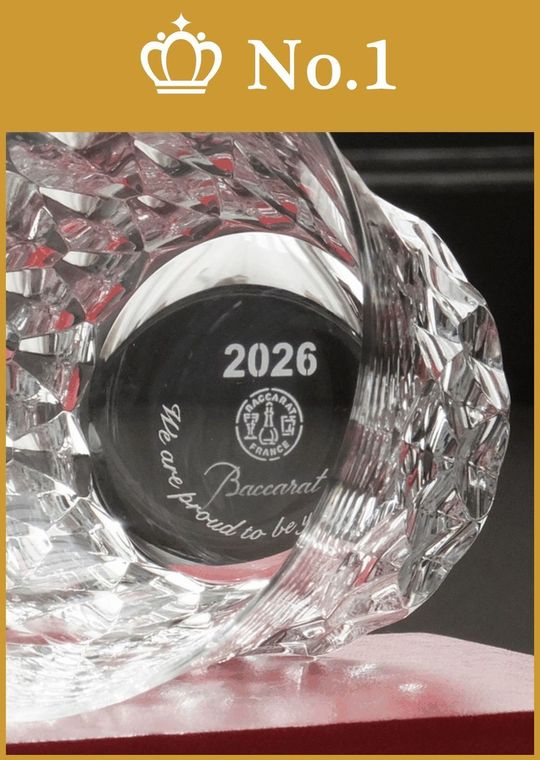 バカラのレッドボックスの上に、恩師への感謝のメッセージを底面に名入れ彫刻したダリア タンブラー 2026を横に倒して置いた写真。グラスを傾けた際に現れる『Thank you』などの刻印がクリスタルの輝きとともに映し出され、教え子一同からの真心を込めた贈り物であることを象徴するエモーショナルなイメージ。