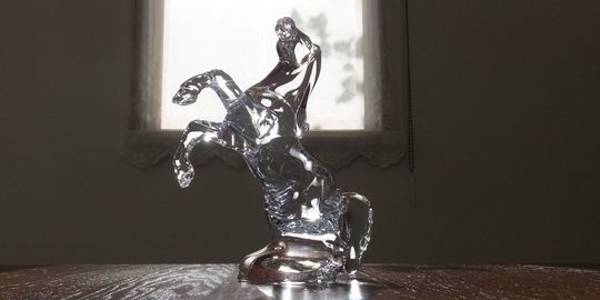 バカラのいななく馬がテーブルの上に置いてある写真。力強く立ち上がった馬の姿が、クリスタルの透明感と光の反射によって、躍動感あふれる美しいフォルムを際立たせています。名入れギフトとしても、成功や飛躍を願う特別な贈り物としても最適な逸品です。