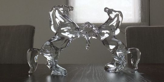 バカラオブジェの商品紹介写真：テーブルの上に、互いに向かい合うように置かれたいななく馬のクリスタルオブジェ2体。躍動感あふれるデザインと、バカラの精緻なクリスタル技術が際立つレイアウトです。