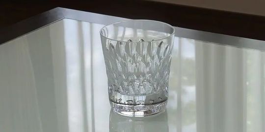 バカラのタンブラー（ロックグラス）の名入れページの商品一覧で使用する写真。バカラ アルマニャックタンブラーがテーブルの上に置かれています。宝石のように美しく輝きが特徴的なグラスが光を反射し、名入れギフトとしての存在感と洗練された美しさを演出しています。