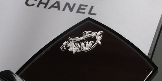 シャネルのコンパクトミラーを開いた際、上部ミラーの左上にイニシャル『J』が名入れ彫刻された写真。鏡を覗くたびに自分のイニシャルが目に留まる、上品でパーソナルなカスタマイズのイメージ。