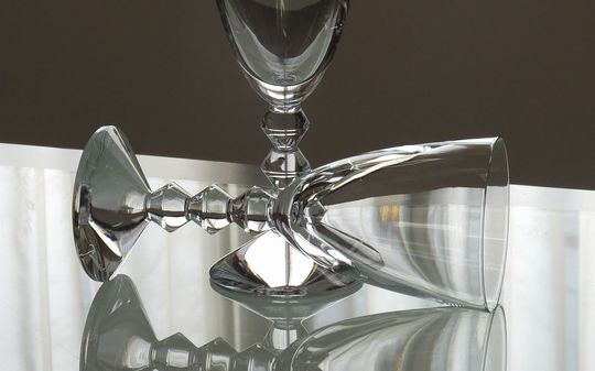 バカラのワイングラス、ベガワイングラスを2客、テーブルの上に置いてある写真。ステムのユニークなデザインと、光を反射して輝くクリスタルが、モダンで優雅な食卓の雰囲気を演出しています。