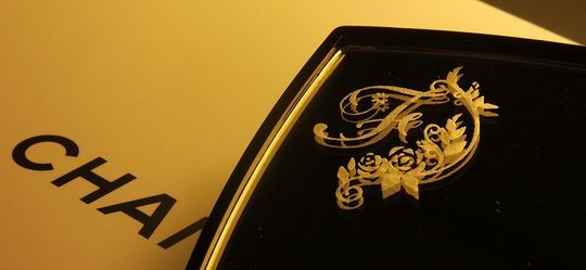 シャネルのコンパクトミラーに、洗練されたイニシャル【F】が装飾された名入れ彫刻。シンプルで上品なデザインが、個性を際立たせる特別なギフト。