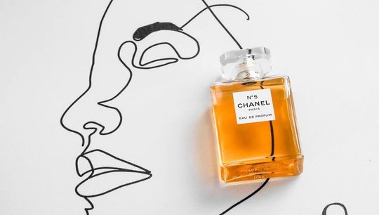 シャネル N5のボトル全体写真。背景には女性のイラストが描かれており、シャネルの象徴的な香水が持つエレガンスと、女性の美しさを表現しています。
