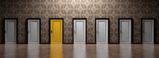 7つある扉の中で、一つだけ黄色い扉がある写真。他の扉が暗い色であるのに対し、黄色い扉が際立っており、何かを選択することを示唆するような、象徴的なイメージです。